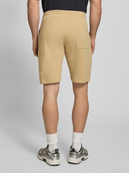 Männermodel trägt Straight Fit Shorts mit Logo-Stitching Modell 'Fillip' von Blend aus Reine Baumwolle mit Strukturmuster, Eingrifftaschen, Gesäßtaschen und elastischem Bund mit Tunnelzug, Rückansicht Ganzkörperansicht.