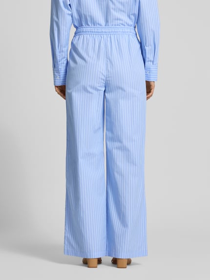 Vrouwenmodel draagt Wide Fit stoffen broek met bloemenprint van Fynch-Hatton, puur katoen, elastische band met tunnelkoord, bloemenmotief. Ganzekörperaanzicht achterzijde.