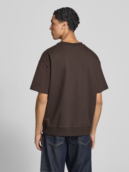 Männermodel trägt Boxy Fit Shirt aus Baumwoll-Mix von Marc O'Polo DENIM in Dunkelbraun, glatte Struktur, Ganzkörperansicht Rückansicht.