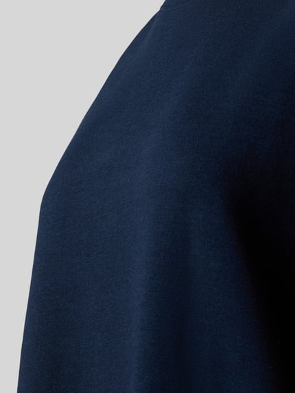 Frauenmodel trägt Relaxed Fit Pyjama-Oberteil mit Rundhalsausschnitt von Christian Berg Woman aus dunkelblauem Baumwoll-Mix mit Stretch-Anteil, Detailaufnahme.