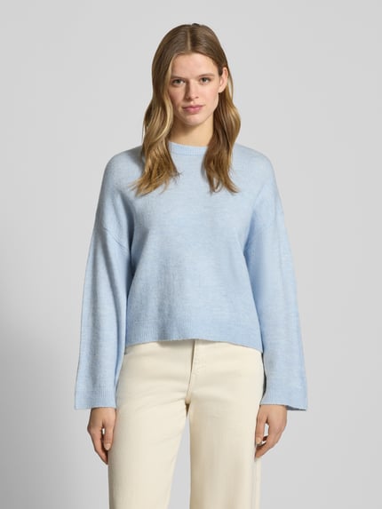 Frauenmodel trägt Relaxed Fit Strickpullover mit Crew Neck Modell 'SIMONI' von Only in Melange-Optik, hellblau, Rundhals, gerippte Abschlüsse, Strickmaterial, Ganzkörperansicht von vorne.