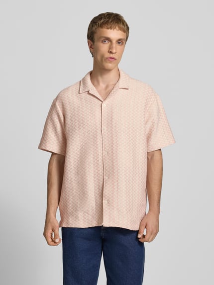 Männermodel trägt Regular Fit Freizeithemd im Allover-Look Modell 'MONTAUK' von Jack & Jones aus Material-Mix mit Baumwoll-Anteil, Reverskragen und Knopfleiste, in hellem Muster vor grauem Hintergrund, Ganzkörperansicht von vorne.