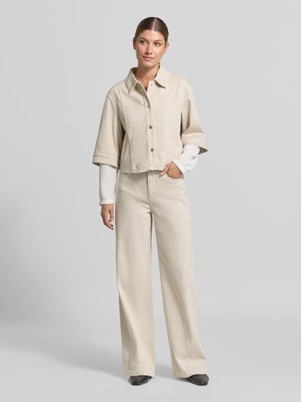 Frauenmodel trägt Relaxed Fit Blazer aus Baumwoll-Mix in Denim-Optik von Marc Cain in Beige mit Umlegekragen und 1/2-Arm, Ganzkörperansicht von vorne. Elastischer Baumwoll-Mix, durchgängige Knopfleiste, Rückenlänge 52 cm, Brustweite 55 cm, Ärmellänge 34 cm.