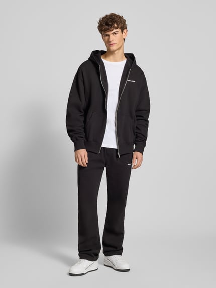Männermodel trägt schwarze Sweathose mit elastischem Bund von Pegador aus Baumwoll-Mix, Label-Stitching, lockerer Schnitt, Ganzkörperansicht von vorne.
