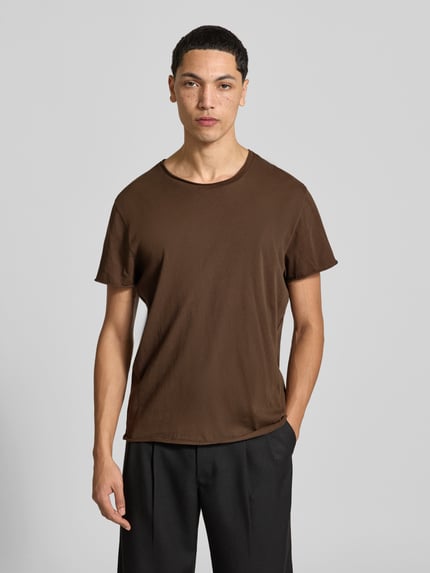 Męski model nosi T-Shirt mit Rollsaum od Filippa K, bawełna, prosty krój, okrągły dekolt, długość tyłu 70 cm, rozmiar M, zdjęcie całej sylwetki z przodu.