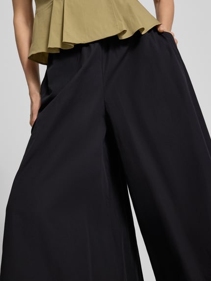 Frauenmodel trägt Wide Fit Stoffhose mit elastischem Bund Modell 'Sunna' von My Essential Wardrobe, Falten-Optik, Nahaufnahme Unterkörper. Bundweite bei Größe 36: 36 cm, Innenbeinlänge bei Größe 36: 58 cm.