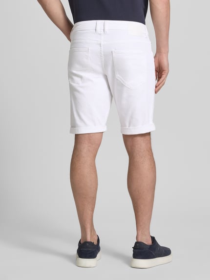 Męski model nosi Slim Fit Jeansshorts aus Baumwoll-Mix von Tom Tailor, białe, 5 kieszeni, szlufki, naszywka z logo, mieszanka bawełny, tkanina stylizowana na denim, zapięcie na guzik i zamek błyskawiczny, Ganzkörperansicht Rückansicht.