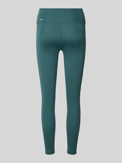 Frauenmodel trägt Skinny Fit Sport-Leggings mit Logo-Print von PUMA, dunkelgrün, glatte Textur, Ganzkörperansicht Rückansicht, Damen Sport-Leggings von PUMA Performance.