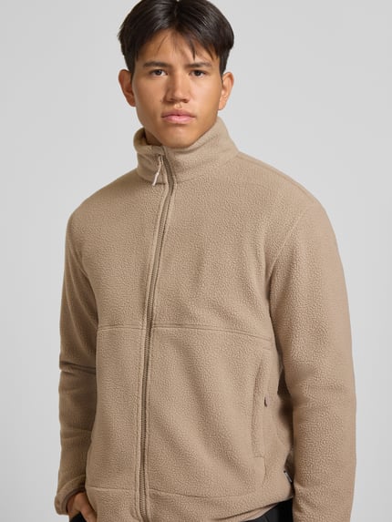 Mężczyznamodel nosi beżową kurtkę z polaru o kroju regular fit ze stójką, model 'JASON' od ONLY & SONS, tekstura miękka, zbliżenie na górną część ciała.