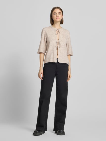 Frauenmodel trägt Regular Fit Cardigan mit Schnürungen Modell 'SIMONI' von Only, beige unifarben, Strickoptik, Ganzkörperansicht von vorne.