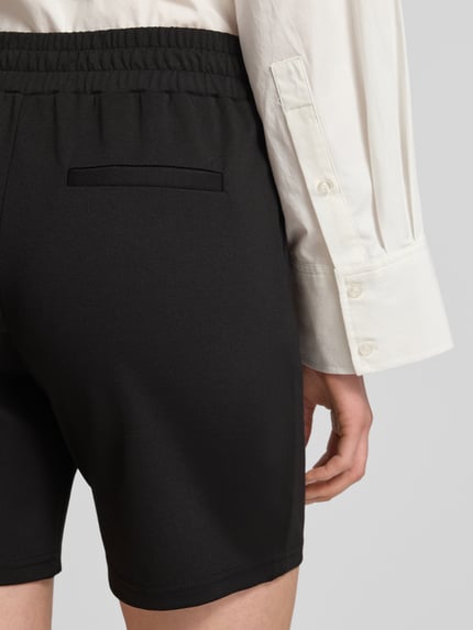 Frauenmodel trägt schwarze Shorts mit elastischem Bund Modell 'Kate' von ICHI aus Material-Mix mit Viskose-Anteil, Detailaufnahme Rückansicht.