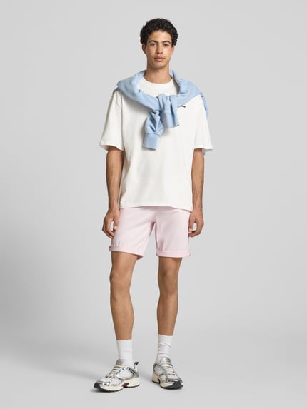 Männermodel trägt Straight Fit Shorts mit Eingrifftaschen Modell 'Bowie' von Jack & Jones aus elastischem Baumwoll-Mix, Ganzkörperansicht von vorne.