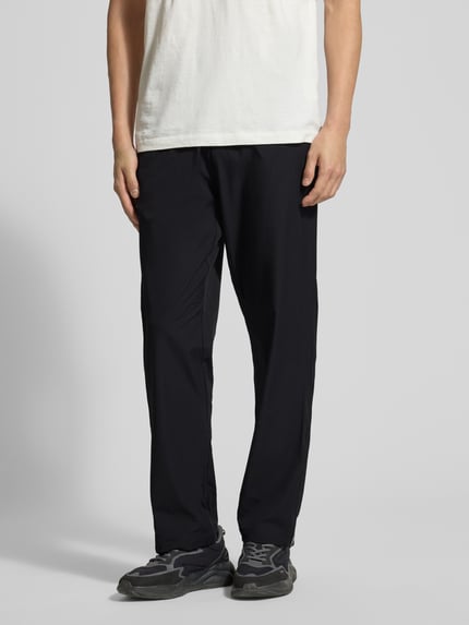 Männermodel trägt Regular Fit Trainingsanzug mit Label-Detail Modell LW_PS Spirit70 TT - PORSCHE X BOSS in unifarben Schwarz, Nahaufnahme Unterkörper, Hosenansicht von vorne, sportliche Textur, elastische Bündchen, BOSS Green.