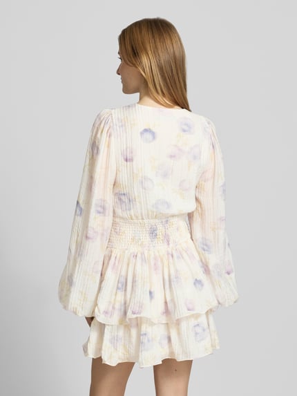 Frauenmodel trägt Minikleid aus Viskose-Mix mit V-Ausschnitt von Gina Tricot, Floraler-Print, Tailliert, Langärmelig, Raffung, Ganzkörperansicht Rückansicht.