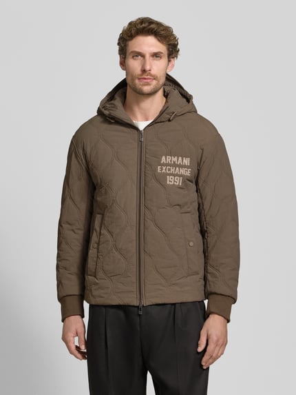 Männermodel trägt Jacke mit Steppnähten und Label-Detail von Armani Exchange in Braun mit Kapuze, Zweiwege-Reißverschluss, Eingrifftaschen, Ganzkörperansicht von vorne.