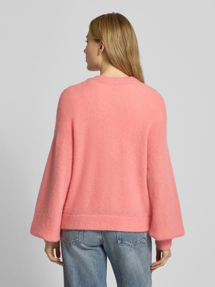 Frauenmodel trägt Strickjacke mit V-Ausschnitt Modell 'Petrinelle Hope' von MSCH Copenhagen in Rosa, lockere Passform, Rückenansicht.