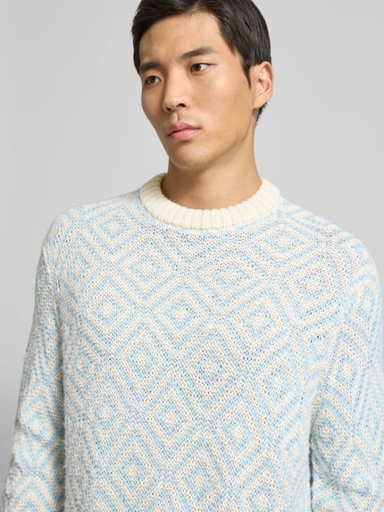 Männermodel trägt Relaxed Fit Strickpullover aus Woll-Mix Modell 'REMI' von SELECTED HOMME, Allover-Muster in Hellblau und Creme, Nahaufnahme Oberkörper.