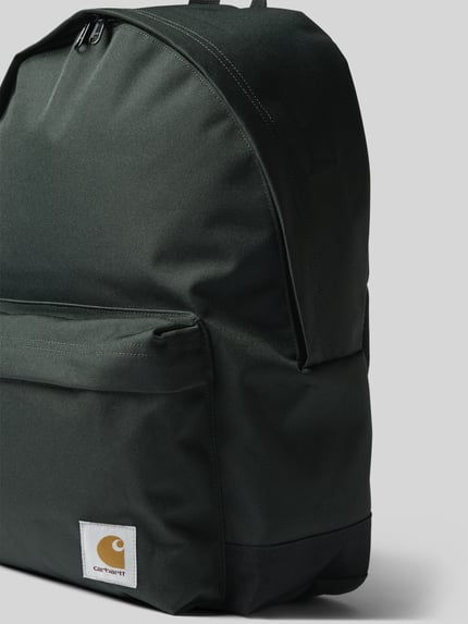 Produktfoto, Rucksack mit Label-Patch Modell 'Jake' von Carhartt Work In Progress aus schwarzem Textil mit Außenfach, Nahaufnahme przodu, Główna przegroda z zamkiem błyskawicznym dwustronnym, przegródka zewnętrzna z zamkiem błyskawicznym, uchwyt, szerokość w rozmiarze 1: 40 cm, długość w rozmiarze 1: 45 cm, głębokość w rozmiarze 1: 14 cm, długość pasków na ramię w rozmiarze 1: 68 cm.