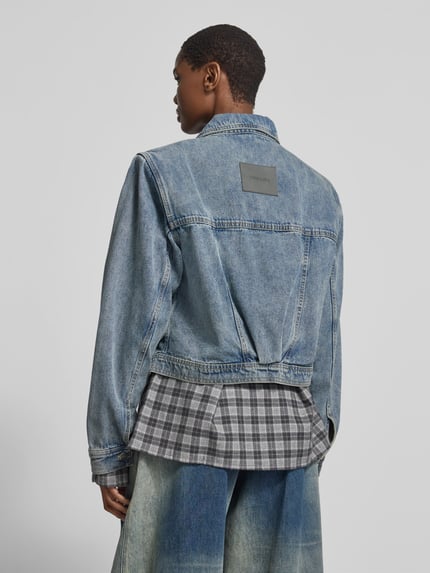 Frauenmodel trägt Funktionsjacke mit Label-Schriftzug Modell 'JEANY' von black palms in Medium Wash Denim, Label-Applikation, Ganzkörperansicht Rückansicht.