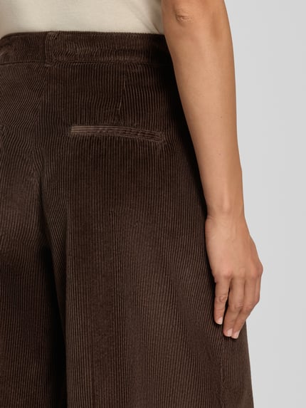 Frauenmodel trägt braune, weit geschnittene Cordhose mit feiner Rippenstruktur, Weite Hose aus reiner Baumwolle Modell 'MELLI S' von Brax, Nahaufnahme Rückansicht, Damen Weite Hose von Brax.