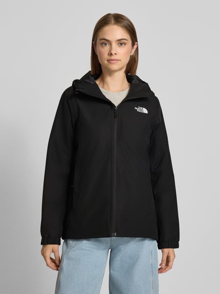 Kobiece model prezentuje kurtkę funkcyjną Regular Fit Funktionsjacke mit Logo-Print Model 'Quest Mono' od The North Face, czarna, gładka faktura, Kaptur, zamek błyskawiczny, Szerokość w rozmiarze S: 40 cm, Długość rękawów w rozmiarze S: 63 cm, Szerokość ramion w rozmiarze S: 40 cm, Długość tyłu w rozmiarze S: 69 cm, widok całej sylwetki z przodu.
