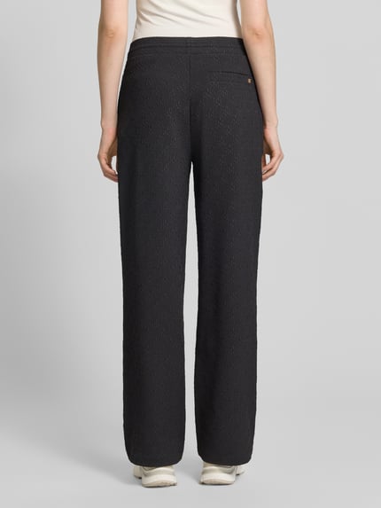 Frauenmodel trägt Regular Fit Sweatpants mit Allover-Muster Modell 'NAYENE' von HUGO, Optik:Allover-Muster, Materialverarbeitung: Sweat, Bundabschluss: elastisch, Gesäßtasche, seitliche Eingrifftaschen, Label-Stitching-Applikation, Ganzkörperansicht Rückansicht.