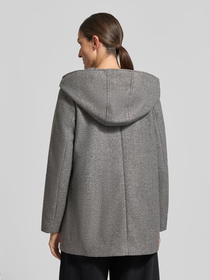 Vrouwenmodel draagt Wollmantel met Kapuze van VERO MODA, grijs, unicolor, dubbele knopen, capuchon, steekzakken, lange mouw, afgeronde zoom, volledig aanzicht van achteren.