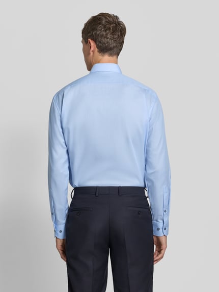 Männermodel trägt Regular Fit Businesshemd mit Brusttasche von OLYMP in Hellblau, feines Webmuster, Ganzkörperansicht Rückansicht.