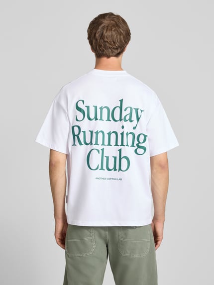 Męski model nosi T-Shirt mit Print und Rundhalsausschnitt von ANOTHER COTTON LAB, bawełna, krój relaxed fit, długość tyłu 69 cm, widok całej sylwetki od tyłu.