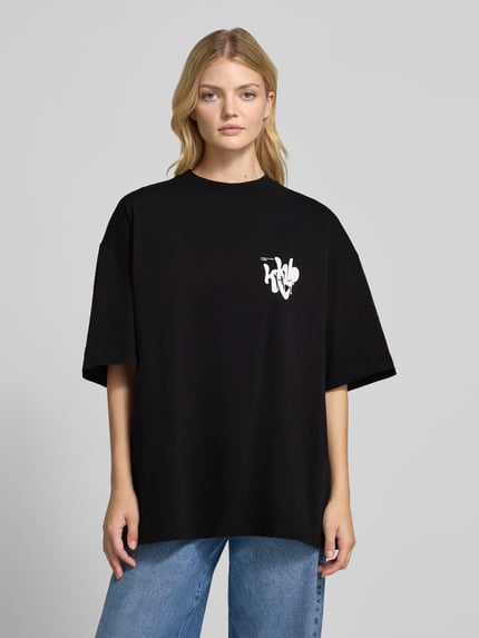 Kobiece model prezentuje Oversized T-Shirt mit Label-Print od Karo Kauer, czarny kolor, bawełna, okrągły dekolt, długość tyłu w rozmiarze S: 73 cm, widok całej sylwetki z przodu.