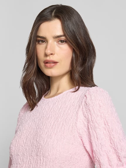 Frauenmodel trägt Blusenshirt mit Strukturmuster Modell 'FALL' von Vila in Rosa, Material-Mix mit Stretch-Anteil, Rundhalsausschnitt, Regular-Fit, Nahaufnahme Oberkörper.