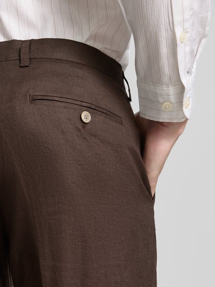 Mężczyznamodel nosi Leinenhose mit Gesäßtaschen von Christian Berg Men, ciemny brązowy len, kanty, krój regular fit, kieszeń z tyłu. Detailaufnahme z tyłu.