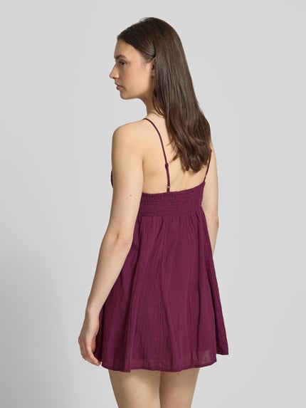 Frauenmodel trägt Minikleid aus reiner Baumwolle Modell 'PANOLA' von Only, Optik: Unifarben, Passform: Tailliert, Mini-Länge, V-Ausschnitt, Smok-Einsatz, Stickerei, Trägerform: verstellbare Spaghettiträger, Material: reine Baumwolle, Ganzkörperansicht Rückansicht.