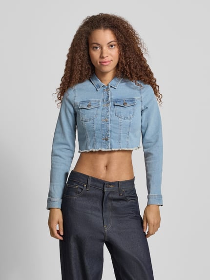 Frauenmodel trägt Slim Fit Jeansjacke aus Baumwoll-Mix Modell 'WONDER' von Only, Denim-Optik, helle Blautöne, Knopfleiste, Brusttaschen, Fransenabschluss, Ganzkörperansicht von vorne.