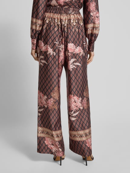 Frauenmodel trägt Stoffhose mit elastischem Bund Modell 'Lunet' von Neo Noir, lockerer Schnitt, florales Muster, Ganzkörperansicht Rückansicht.