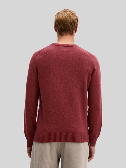 Männermodel trägt Pullover mit Logo-Detail von MARC O'POLO in melierter Strickoptik, strukturierte Oberfläche, Ganzkörperansicht Rückansicht.