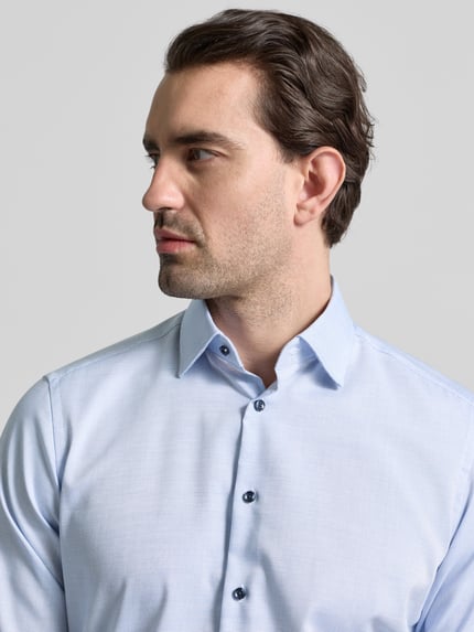Männermodel trägt Regular Fit Business Hemd aus Baumwolle mit Kentkragen von Christian Berg Men, hellblauer Stoff, Nahaufnahme Oberkörper.