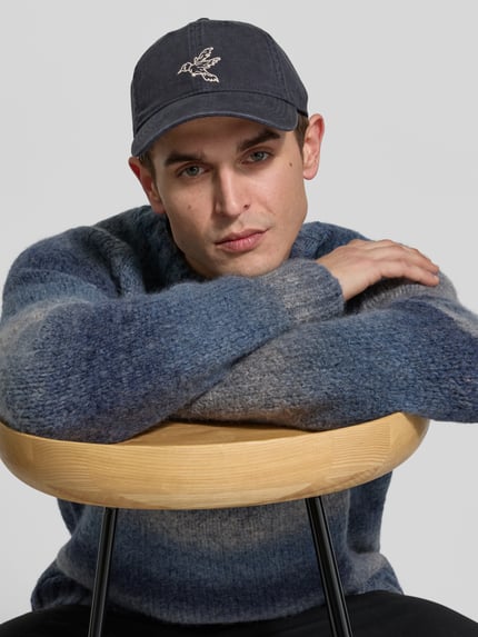 Męski model nosi czapkę z daszkiem Basecap aus reiner Baumwolle od Forét, wyhaftowany motyw, tkanina stylizowana na denim, regulacja z tyłu, widok na górną część ciała z przodu.