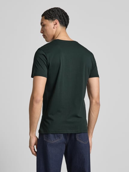 Männermodel trägt Herren T-Shirt mit Label-Details Modell 'BASIC' von Alpha Industries in Dunkelgrün, Reine Baumwolle, Gerader-Schnitt, Rückenansicht Ganzkörperansicht Rückansicht.