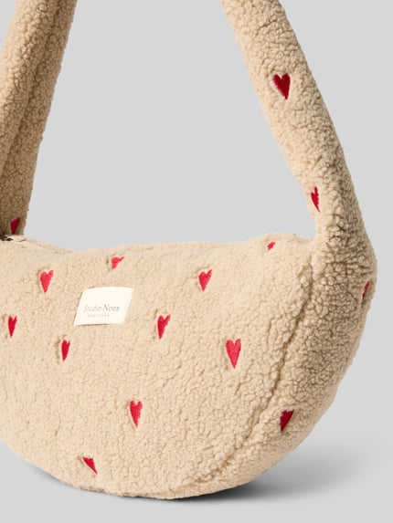 Produktfoto, Shoulder Bag mit Teddyfell Modell 'Hearts' von STUDIO NOOS in Beige mit roten Herzmustern, strukturiertes Teddyfell, Nahaufnahme Oberteil, Hauptfach mit Reißverschluss, Logo-Patch, Innentasche mit Reißverschluss, Schulterriemen