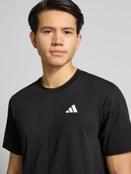 Männermodel trägt T-Shirt mit Logo und Rundhalsausschnitt von adidas Training, Material-Mix mit Baumwoll-Anteil, Regular-Fit, Nahaufnahme Oberkörper.