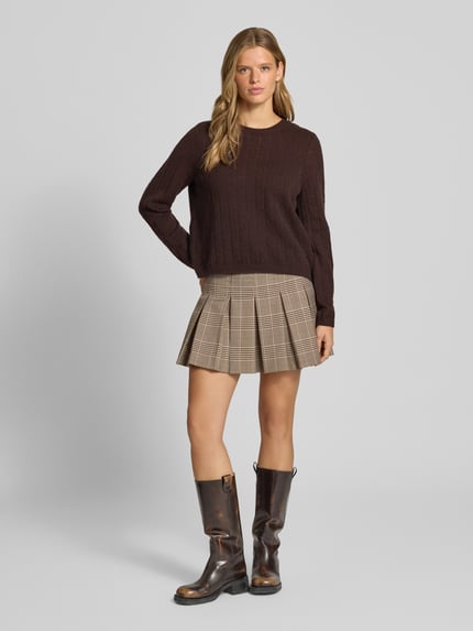 Frauenmodel trägt Regular Fit Pullover mit gerippten Ärmelbündchen Modell 'ADA' von PIECES in Dunkelbraun, Strukturstrick, Ganzkörperansicht von vorne.