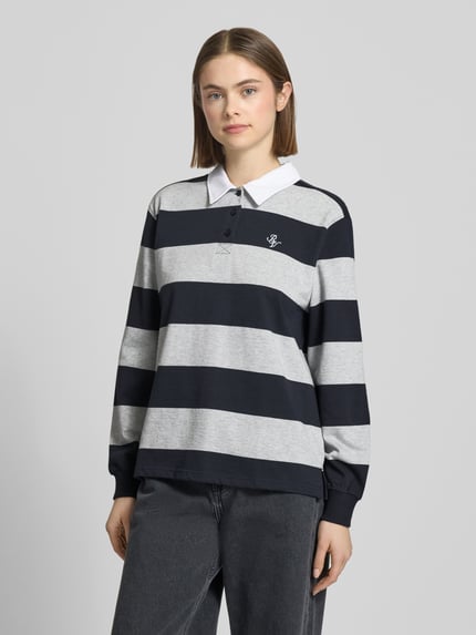 Frauenmodel trägt Polo-Langarmshirt mit Streifen und kontrastiger Knopfleiste von Review, reine Baumwolle, Regular Fit, gesticktes Logo, Ganzkörperansicht von vorne.