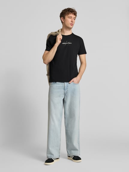 Männermodel trägt Herren T-Shirt mit Label-Detail Modell 'Foam' von Alpha Industries, Reine Baumwolle, Gerader-Schnitt, Rundhalsausschnitt, Ganzkörperansicht von vorne.