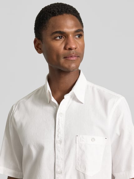 Männermodel trägt Regular Fit T-Shirt aus Baumwoll-Mix von Lerros in Weiß mit Rundhalsausschnitt und Label-Detail, Nahaufnahme Oberkörper.