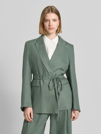 Frauenmodel trägt Anzugblazer mit Reverskragen von Jake*s Collection in sanftem Grün mit Stoffband und Paspeltaschen, taillierte Passform, Rückenlänge 65 cm, Brustweite 60 cm, Ärmellänge 42 cm, Nahaufnahme Oberkörper.