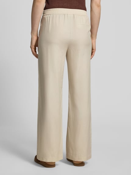Frauenmodel trägt Stoffhose aus Lyocell-Mix mit elastischem Bund von Comma, Relaxed-Fit, Gesäßtasche, beige, Ganzkörperansicht Rückansicht. Bundweite bei Größe 36/32: 39 cm, Innenbeinlänge: 78 cm, Lyocell-Mix mit Leinen-Anteil, Damen.