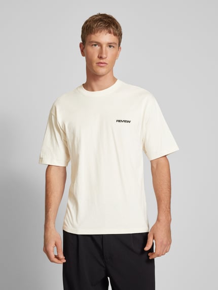 Mannelijk model draagt Relaxed Fit T-shirt uit puur katoen van REVIEW, geborduurd logo, met korte mouwen, ruglengte maat M 68 cm, geheelopname vooraan.