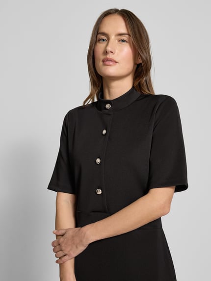 Modelka kobieca nosi czarne Kleid mit Stehkragen und Knopfleiste Modell 'Tibra' od JOOP!, krótki rękaw, długość mini, ujęcie z przodu, zbliżenie na górę ciała.