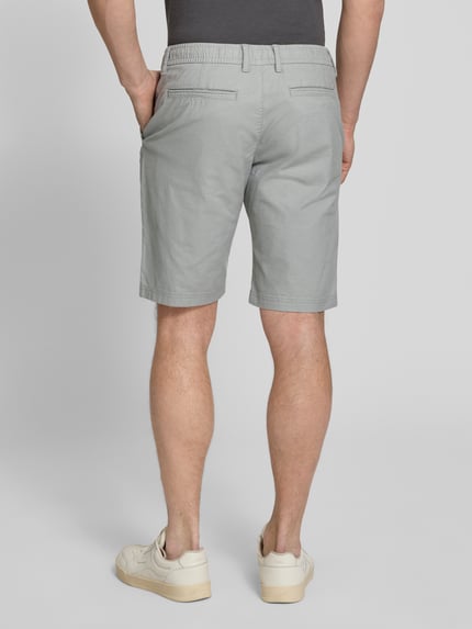 Männermodel trägt Regular Fit Chinoshorts aus Baumwoll-Mix Modell 'PHOENIX' von s.Oliver RED LABEL, Bi-Color Optik, Bundabschluss elastisch, 5-Pocket-Design, Ganzkörperansicht Rückansicht.